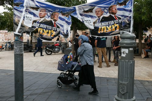 A woman passes by a banner depicting Israeli Prime Minister Benjamin Netanyahu and US President Donald Trump day after the country held a national election, in Jerusalem, October 28 , 2026. © Ronen Zvulun, Reuters